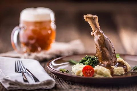 Lamb shank.Confit lamb shank with mashed potatoes spinach and draft beer in.. Stock Photos
