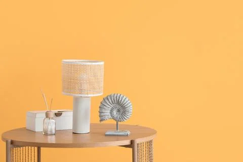 Lamp and reed diffuser on coffee table near orange wall in living room, close Stock Photos