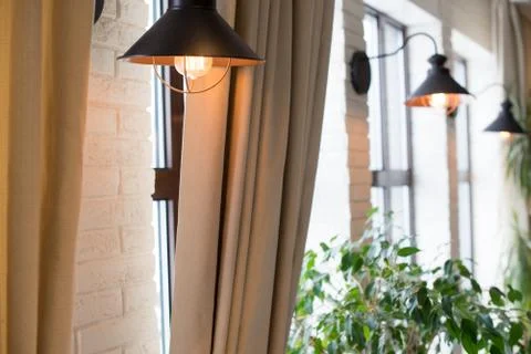 A lamp on the background of a window and a wall with curtains Stock Photos