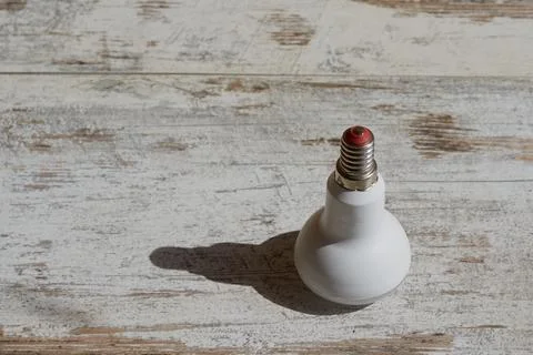 Lamp casting a shadow on a wooden table, daylight on a twisted lamp on a tabl Foto stock
