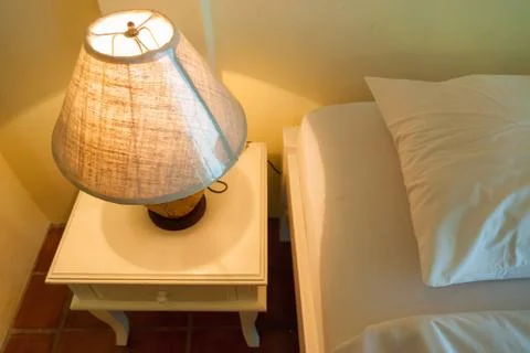 Lamp on a night table next to a bed Stock Photos