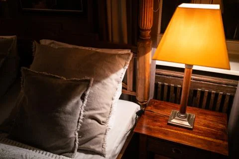 Lamp on a night table next to a bed Stock Photos