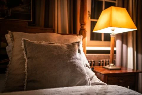 Lamp on a night table next to a bed Stock Photos