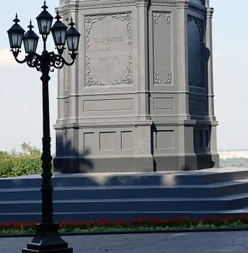 Lamp post. The foundation of the monument. Planted red flowers. In the backgr Stock Photos