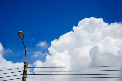 A lamp post on the huge white clouds contrast with blue sky in sunny day back Stock Photos