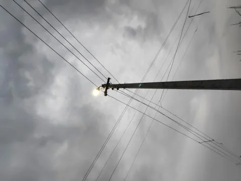 Lamp post with lighten bulb in cloudy weather and wires Stock Photos