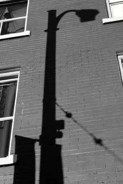 Lamp post shadow cast on a brick wall  Stock Photos