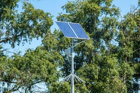 Lamp post with solar panel system on road with blue sky and trees. Autonomous 스톡 사진