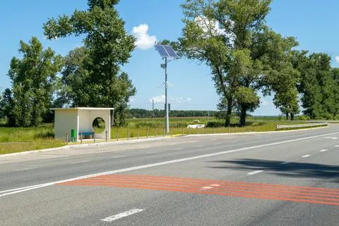 Lamp post with solar panel system on road with blue sky and trees. Autonomous Stock Photos
