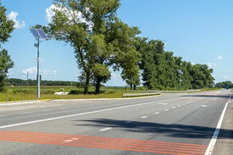 Lamp post with solar panel system on road with blue sky and trees. Autonomous Stock Photos