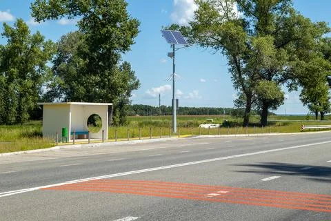 Lamp post with solar panel system on road with blue sky and trees. Autonomous Stock Photos