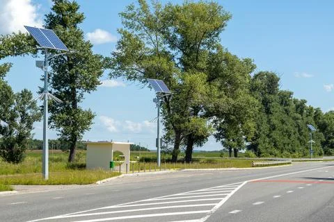 Lamp post with solar panel system on road with blue sky and trees. Autonomous Stock Photos