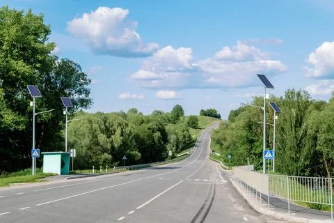 Lamp post with solar panel system on road with blue sky and trees. Autonomous Stock Photos
