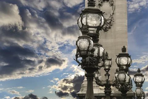 Lamp posts on Alexander III Bridge against the sky with clouds. Paris, France Stock Photos