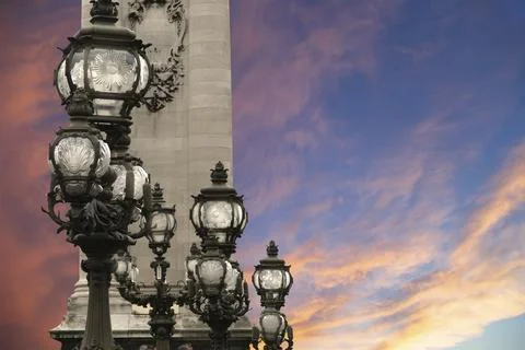 Lamp posts on Alexander III Bridge against the sky at sunset. Paris, France Stock Photos