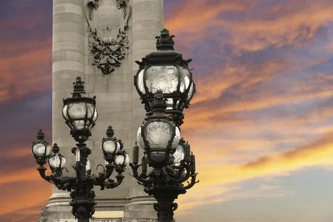 Lamp posts on Alexander III Bridge against the sky at sunset. Paris, France Stock Photos