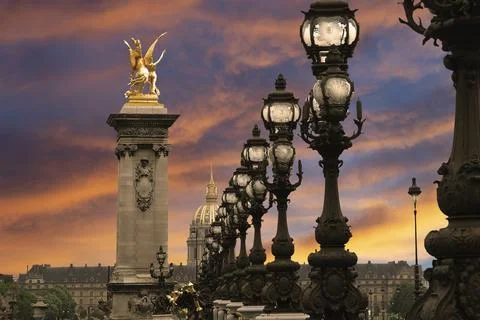 Lamp posts on Alexander III Bridge against the sky at sunset. Paris, France Stock Photos