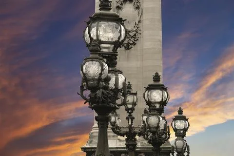 Lamp posts on Alexander III Bridge against the sky at sunset. Paris, France Stock Photos