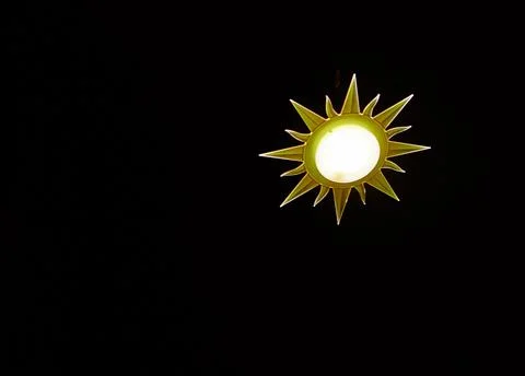 Lamp in the shape of the sun on black background Stock Photos
