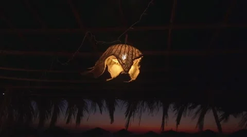 Lamp sways in the wind in small cafe on the beach after sunset Stock Footage 59795084