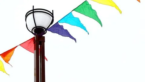 A lamppost and colorful triangular flags fluttering in the wind against an ov 스톡 사진