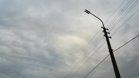 A lamppost with wires on the background of a cloudy dense sky. Cloudy weather Stock Photos