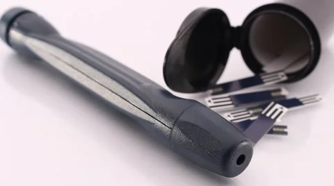 Lancing Device and Test Strips Used by Diabetes Lying on a White Shiny Table Stock Footage 56479593