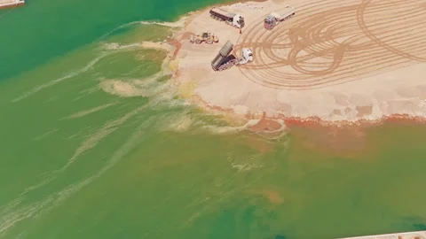 Land reclamation project with dump trucks creating an artificial island Stock-Footage 345007451
