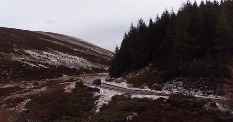 Land Rover turning around sharp corner on mountainous road drone aerial 4K Stock Footage 104585296