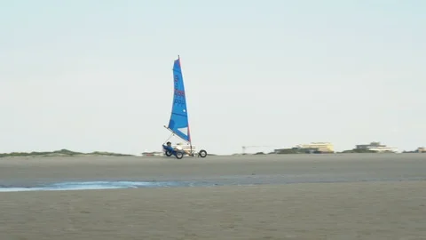 Land sailing - A pilot in a sail wagon rolls through the deserted sandy beach Stock Footage 90393660