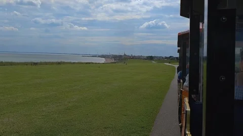 A land train heading towards a coastal town with ocean views Stock-Footage 202938652