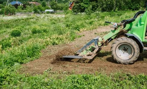 Land work by the territory improvement. Small tractor with a ground leveler for Stock Photos