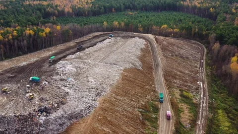 Landfill. A huge pile of garbage surrounded by forest. Garbage trucks carry Stock Footage 342833821