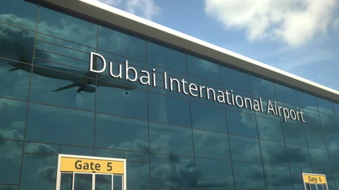 Landing airplane reflects in the modern windows with Dubai International Airport Stock Footage 154276640
