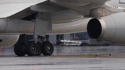 Landing gear and engine of jetliner taxiing on wet airport ramp. Sunlight spots 스톡 동영상 94543353