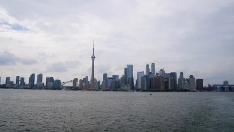 Landing plane flies low over water across downtown Toronto city skyline Stock Footage