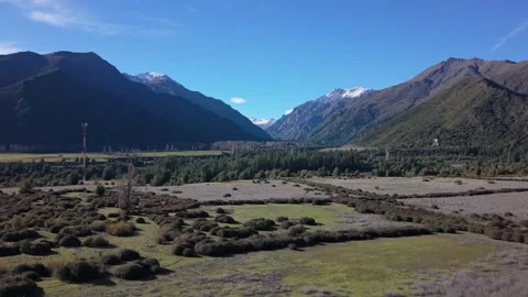 Landing shot descending over open shrubland toward a dense forested valley Stock Footage 346557287