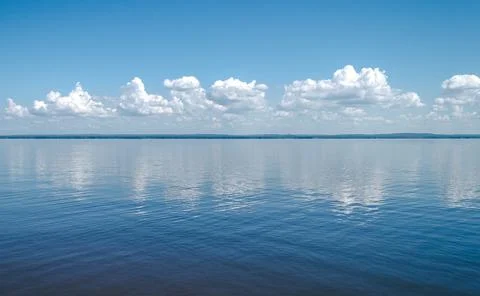 Landscape of calm lake, blue sky with clouds reflected in the water Stock Photos