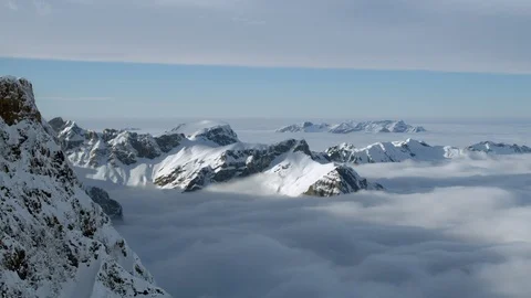Landscape of clouds swinging up and down between tall Swiss Alps on sunny day Stock Footage 129099025