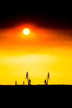 Landscape of a cranes in a harbor at sunset with clouds Stock Photos