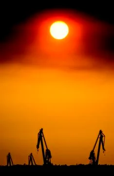 Landscape of a cranes in a harbor at sunset with clouds Stock Photos