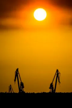 Landscape of a cranes in a harbor at sunset with clouds Stock Photos