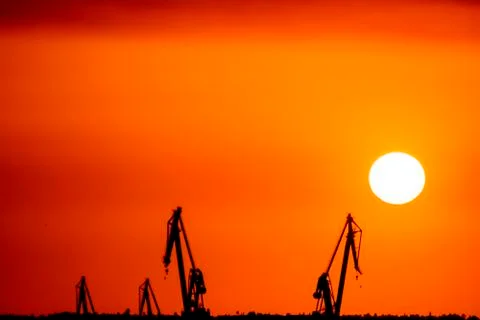 Landscape of a cranes in a harbor at sunset with clouds Stock Photos