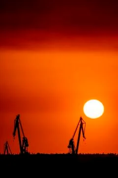 Landscape of a cranes in a harbor at sunset with clouds Foto stock