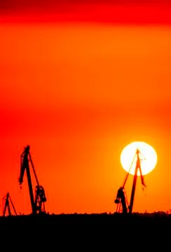 Landscape of a cranes in a harbor at sunset with clouds Stock Photos