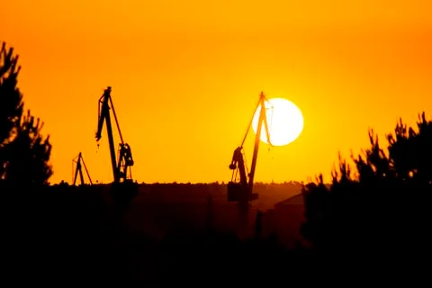 Landscape of a cranes in a harbor at sunset with clouds Stock Photos