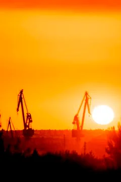 Landscape of a cranes in a harbor at sunset with clouds Foto stock