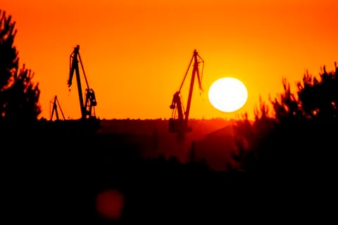 Landscape of a cranes in a harbor at sunset with clouds Stock Photos