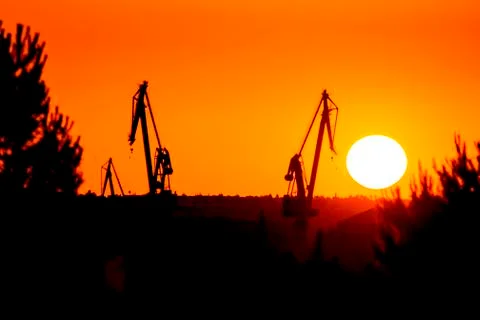Landscape of a cranes in a harbor at sunset with clouds Stock Photos