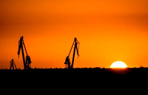 Landscape of a cranes in a harbor at sunset with clouds Stock Photos
